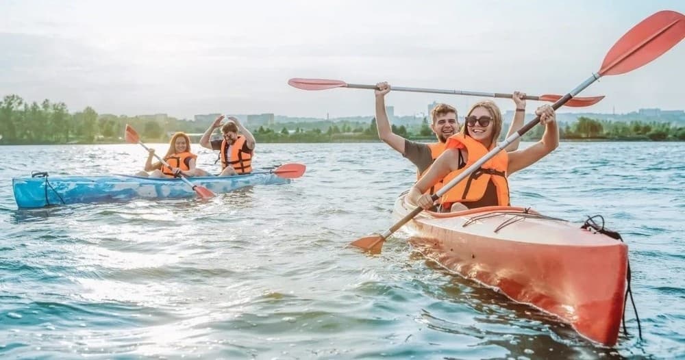 Group kayaking in red kayaks across open water, team paddling