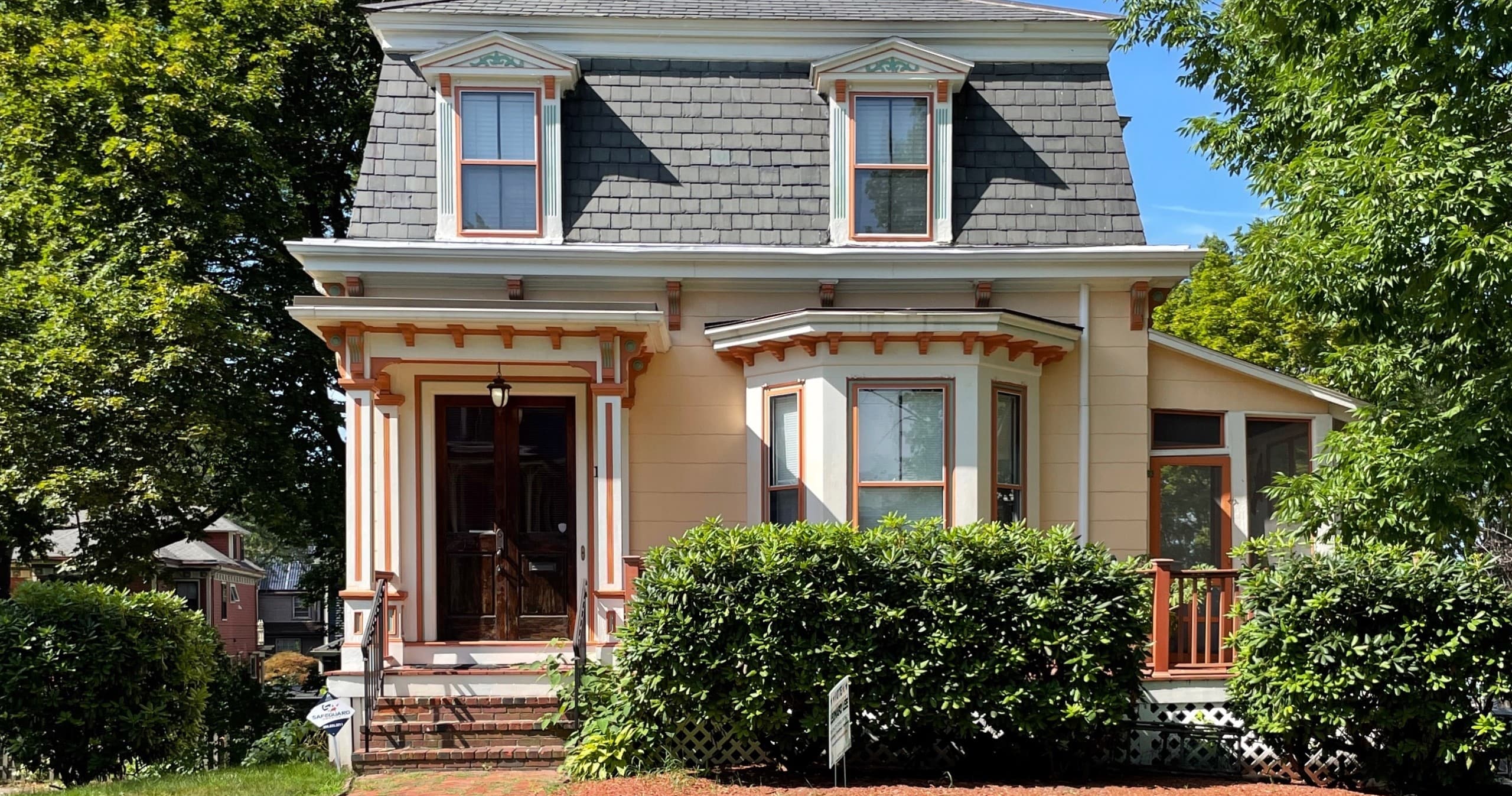 Victorian house with front porch in leafy suburban yard