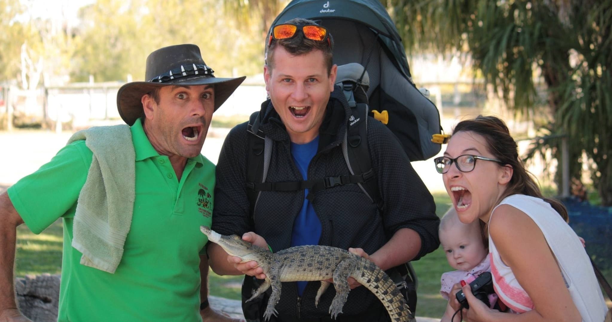 Visitors holding juvenile crocodile at outdoor wildlife park encounter