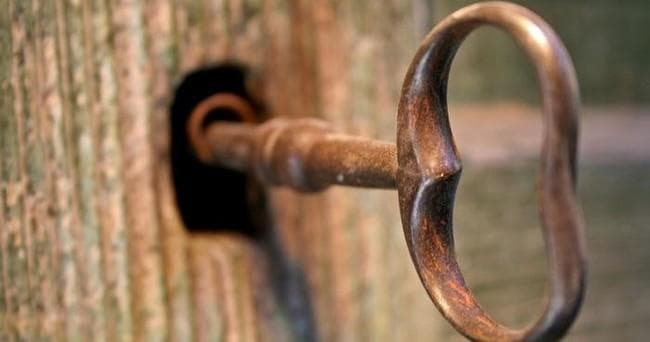 Antique key in door keyhole, close-up escape game prop