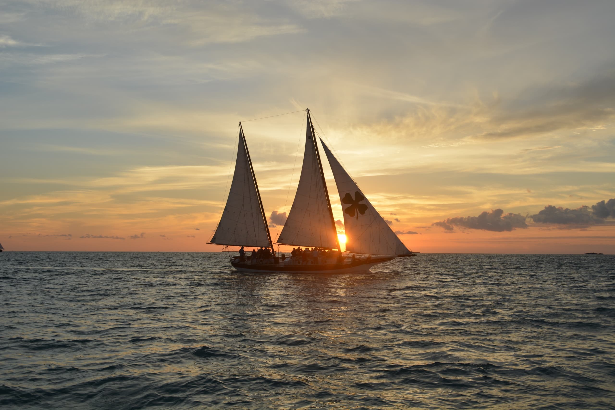 Two sailboats silhouetted at sunset over Key West waters