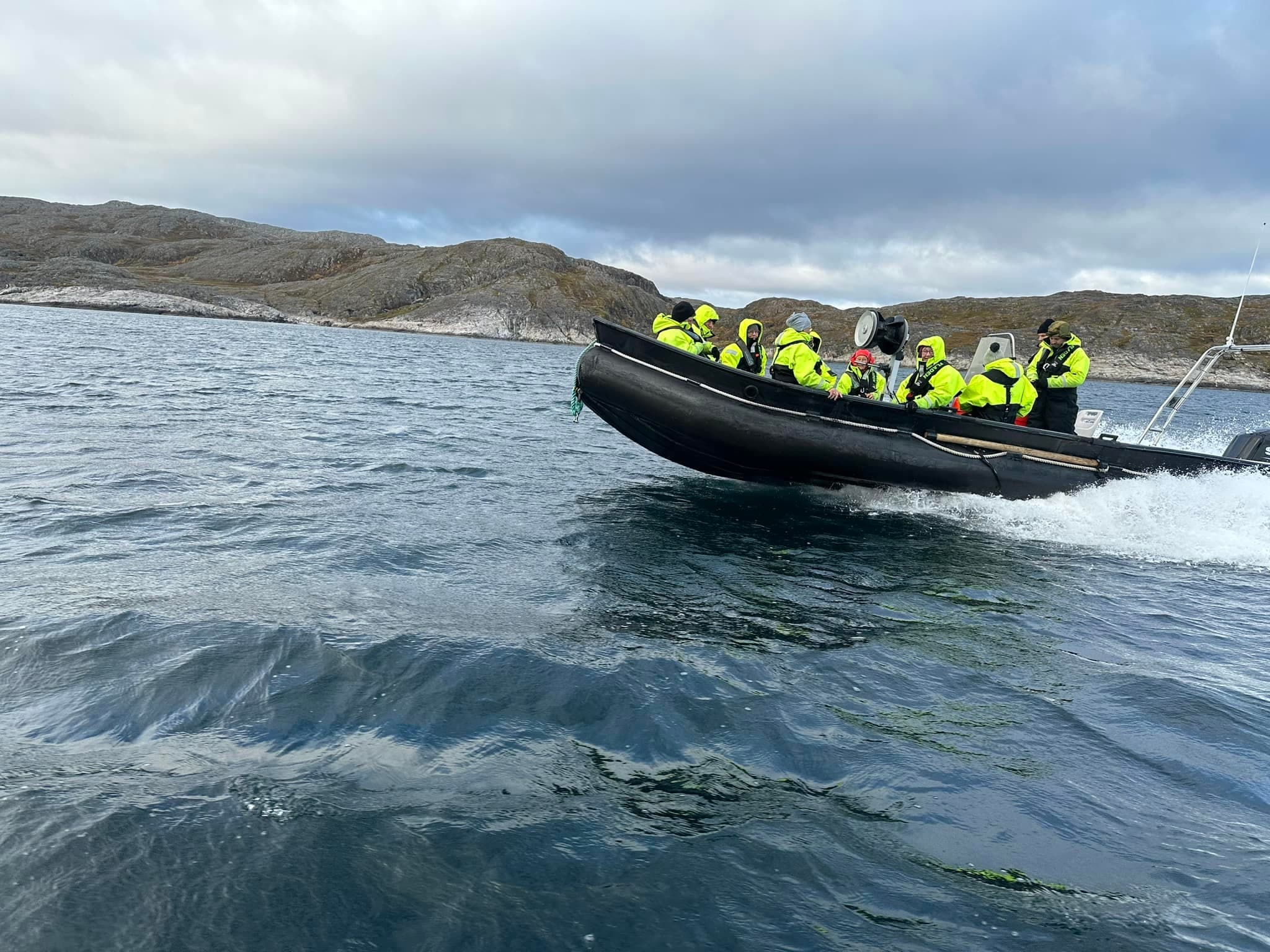 RIB boat leaping waves with tourists in neon jackets