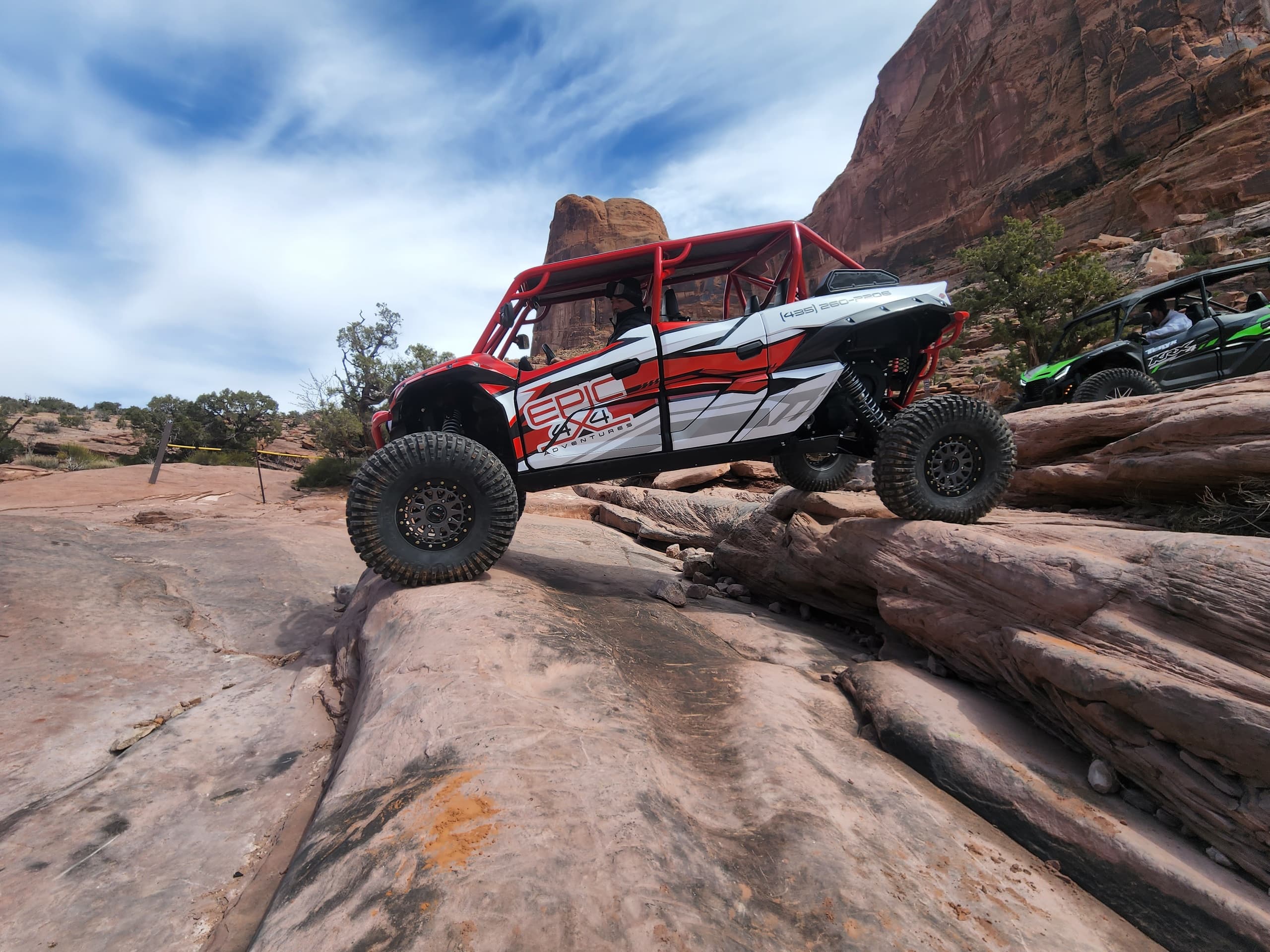 UTV climbing rocky slickrock trail with desert canyon backdrop