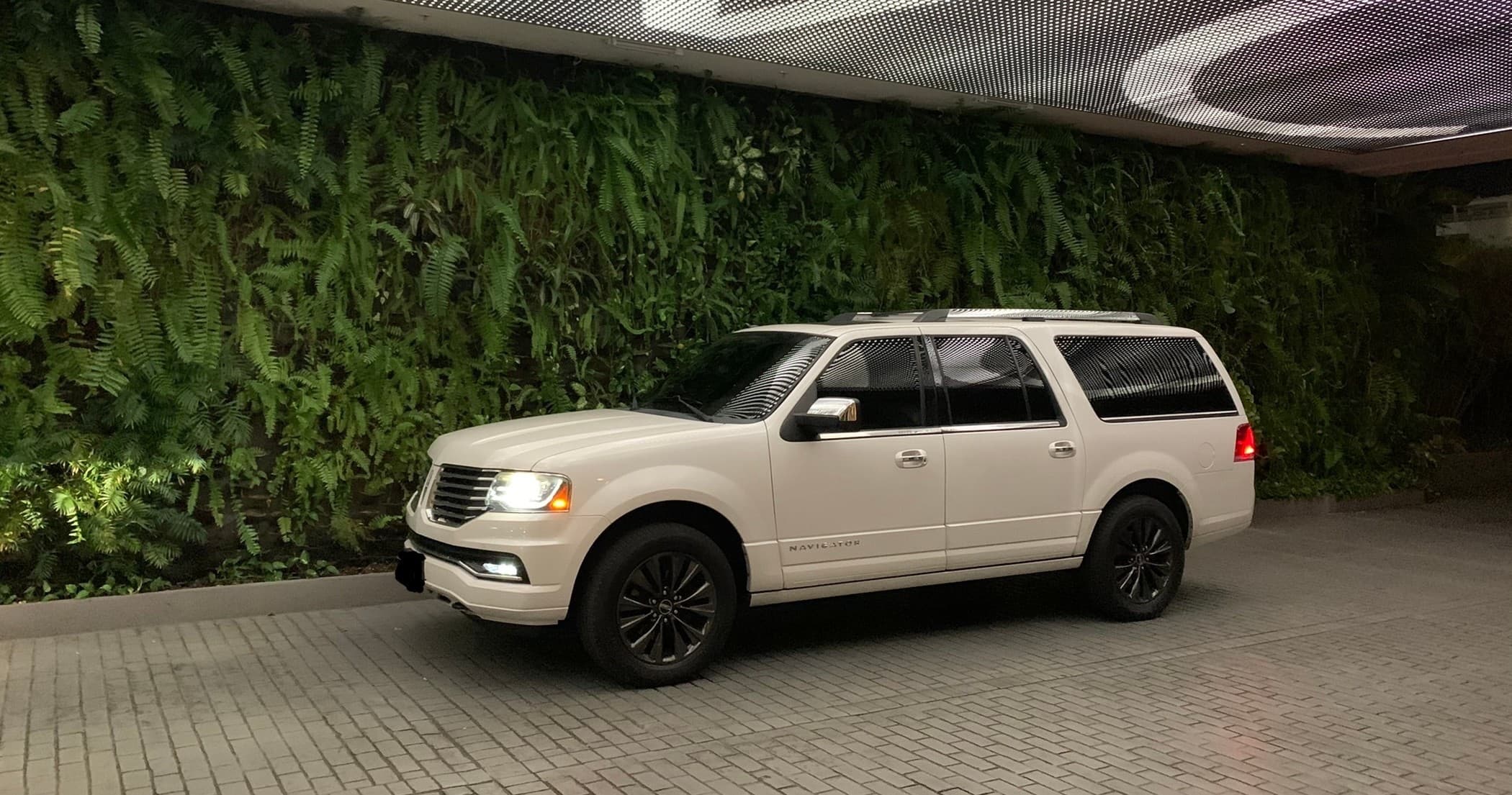 White SUV under covered valet with vertical green wall backdrop