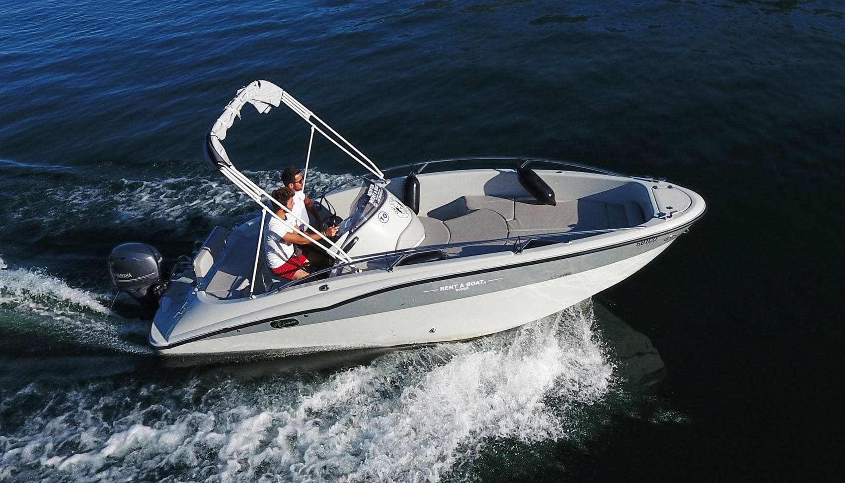 Outboard motorboat cutting through dark lake water, active ride