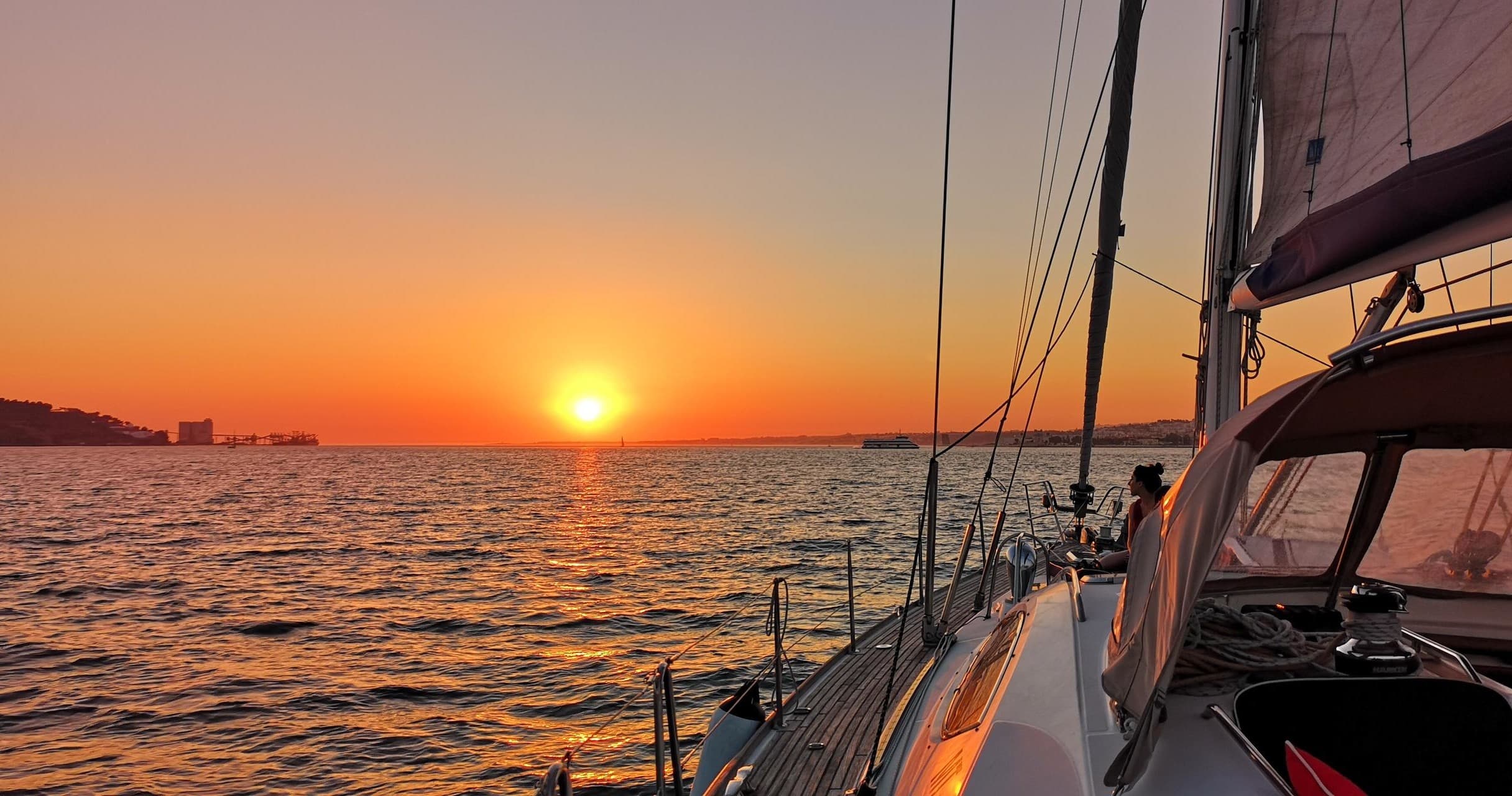 Sunset sail on calm sea near Lisbon, yacht deck and orange sky