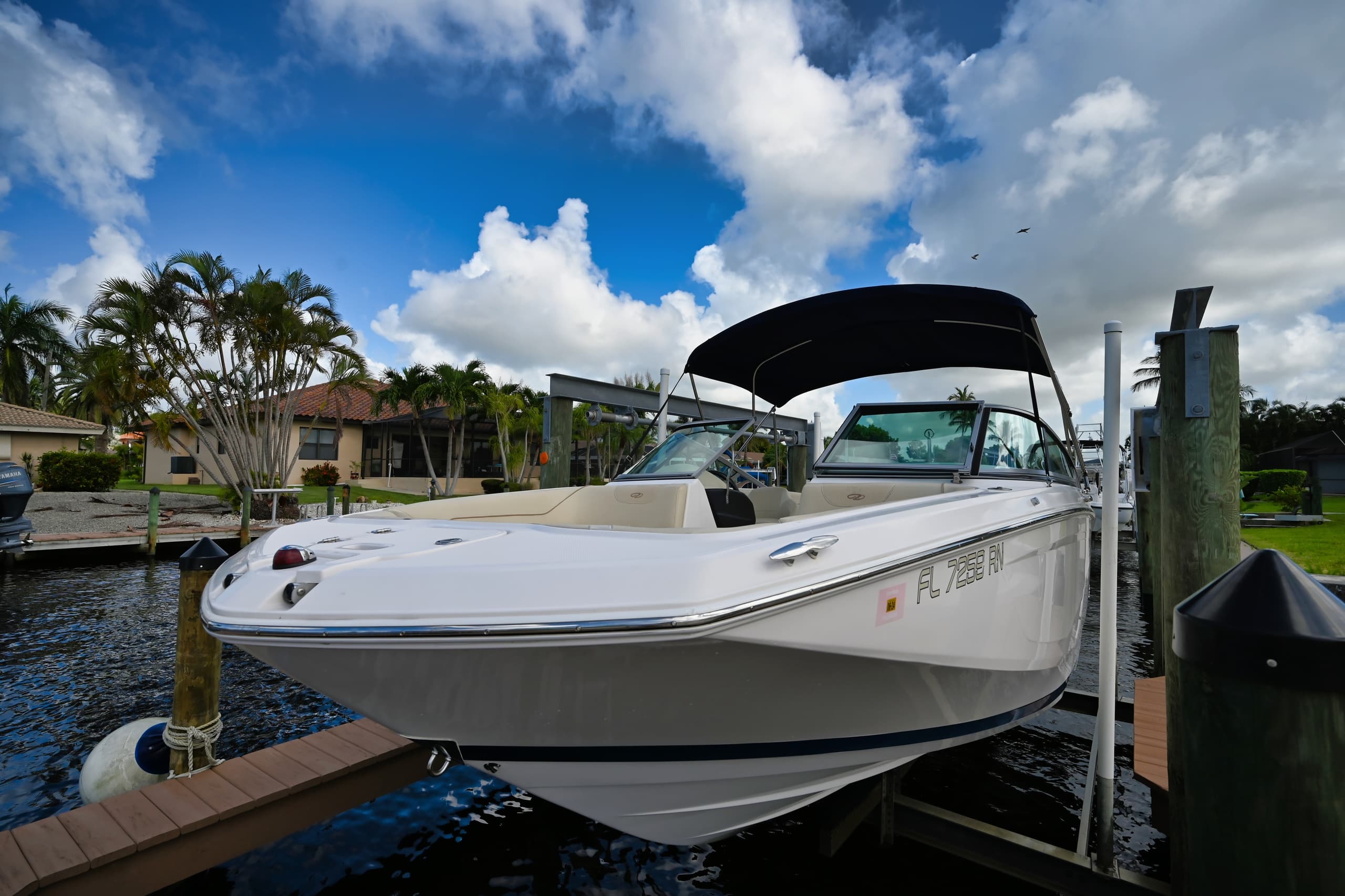 White bowrider boat tied to dock with dramatic cloudy sky