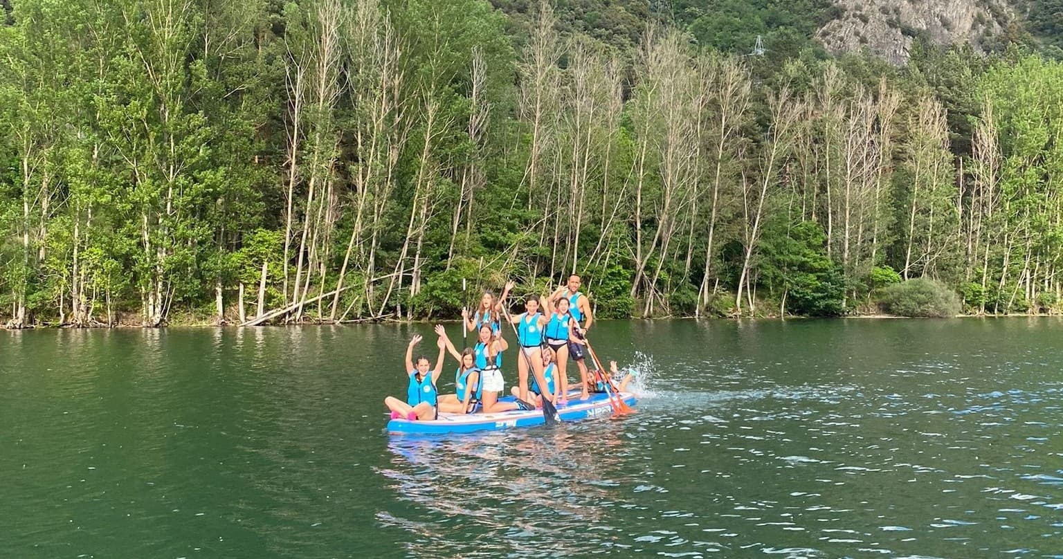 Group paddleboarding across green mountain lake near forest shore