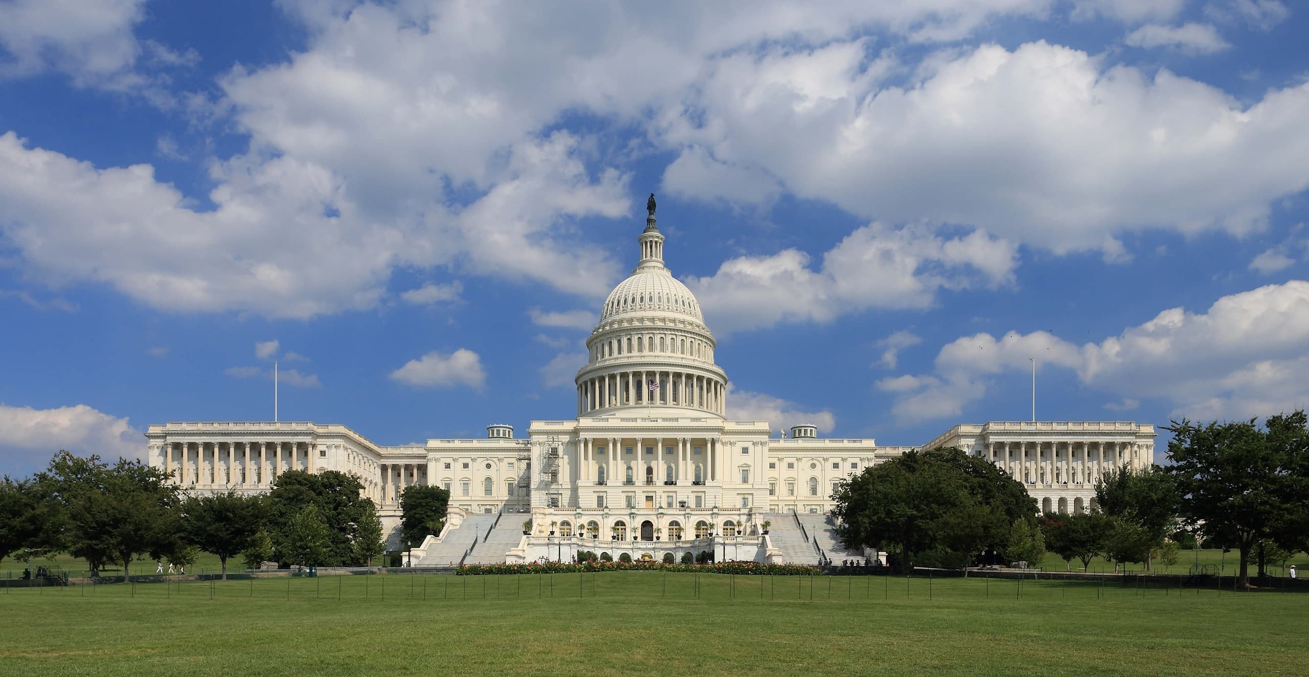 U.S. Capitol building with green lawn and blue sky, Washington DC