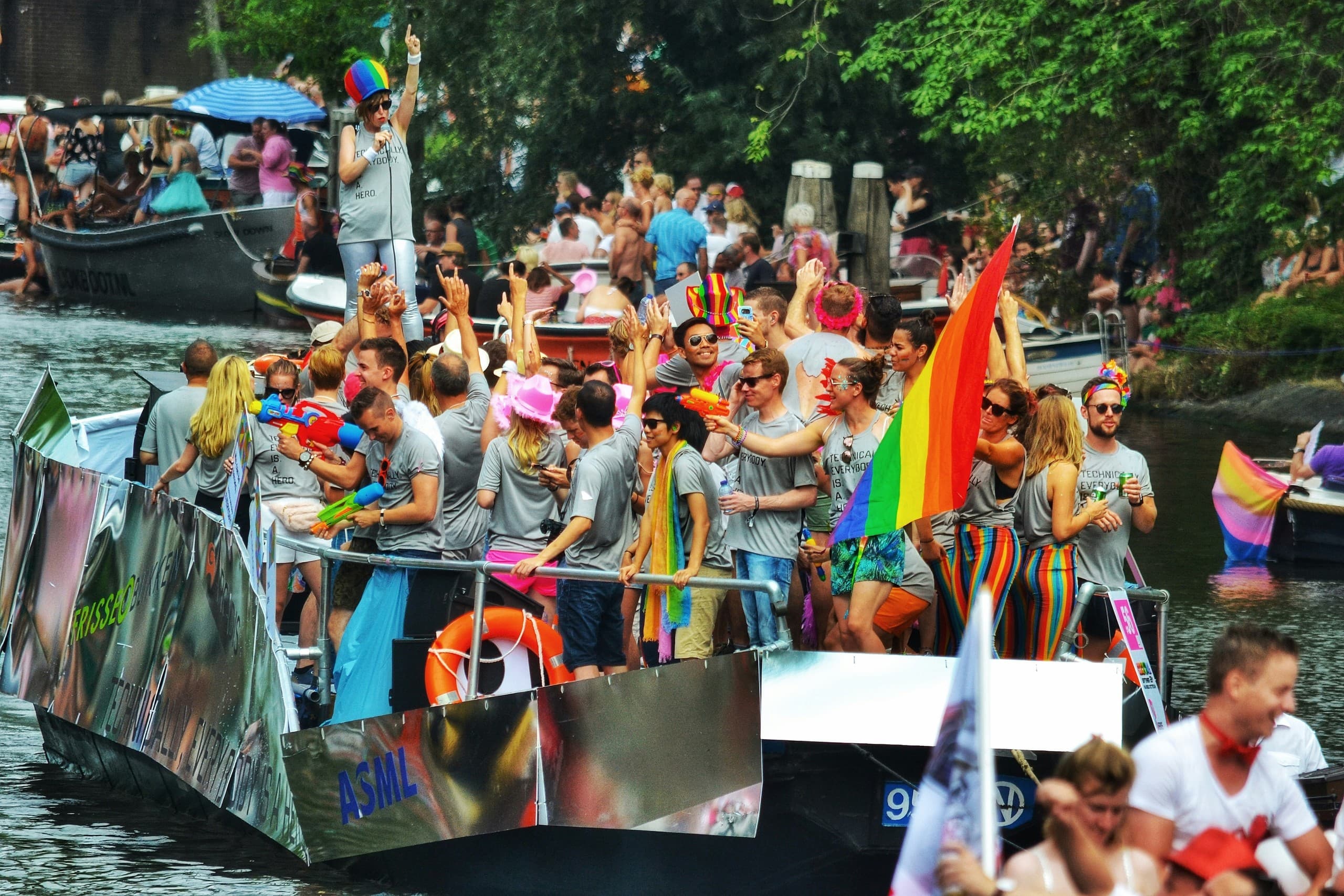 Colorful Pride boat parade on Amsterdam canal with cheering crowd