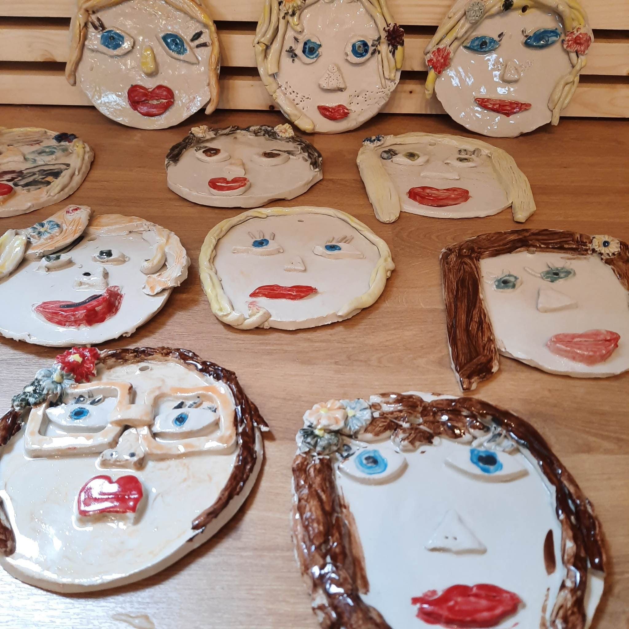 Colorful hand-painted ceramic face plates drying on table