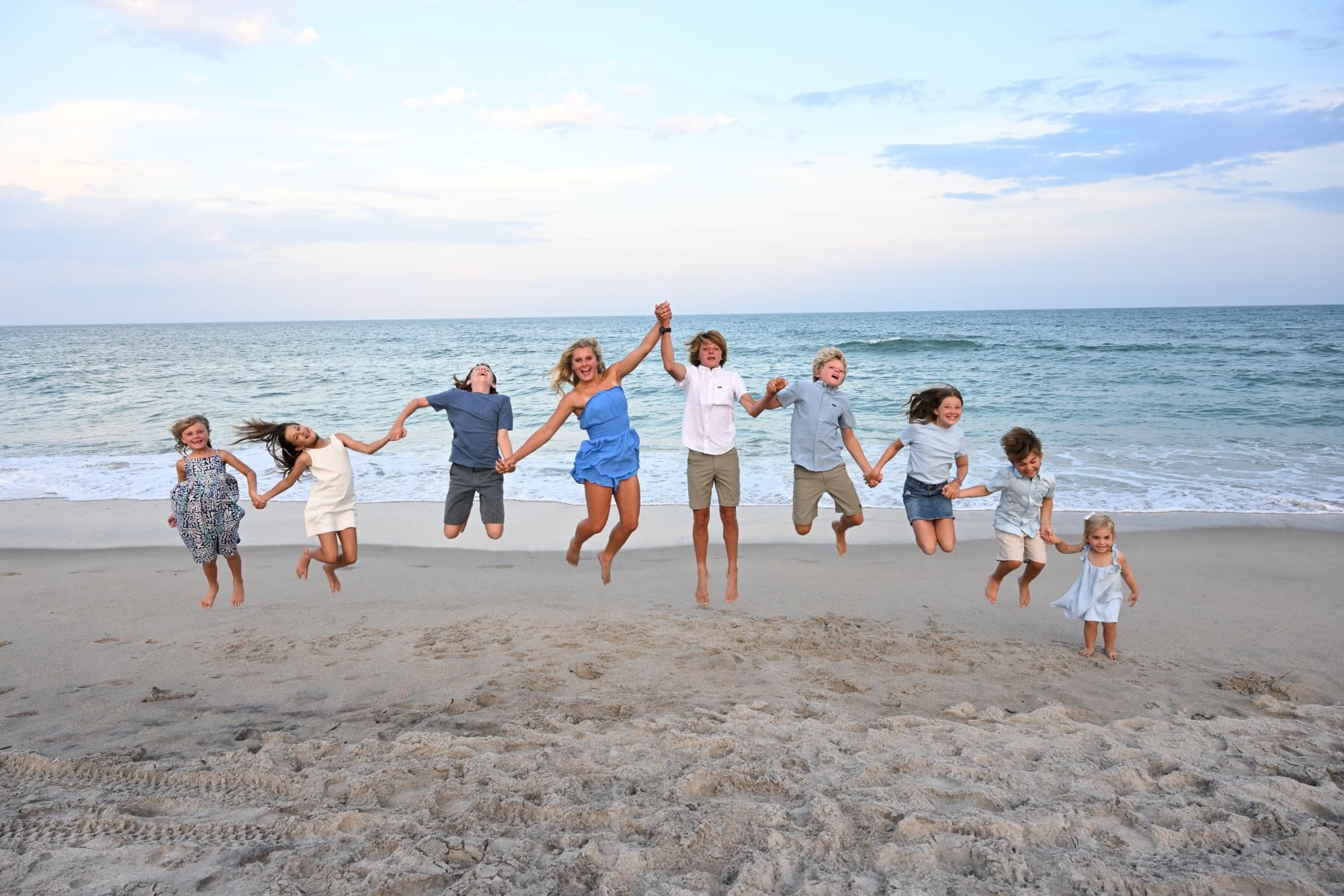 Large family jumping and running together on sandy beach