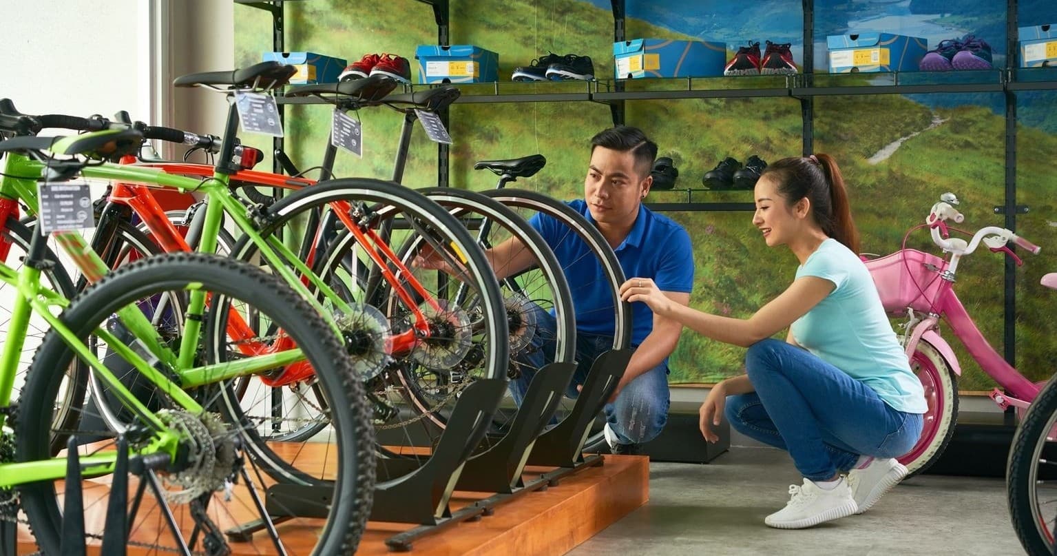 Customers examining mountain and road bikes in shop aisle