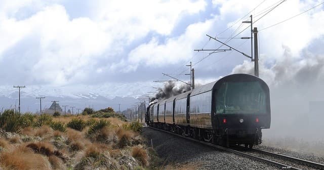 Scenic heritage rail journey through windswept grasslands, clouds