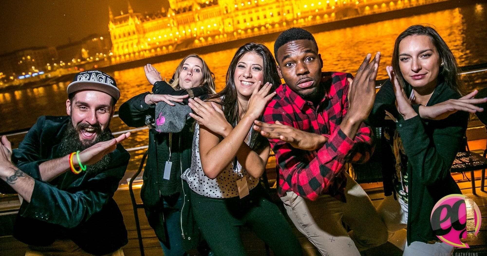 Friends dancing on Budapest river boat with illuminated Parliament