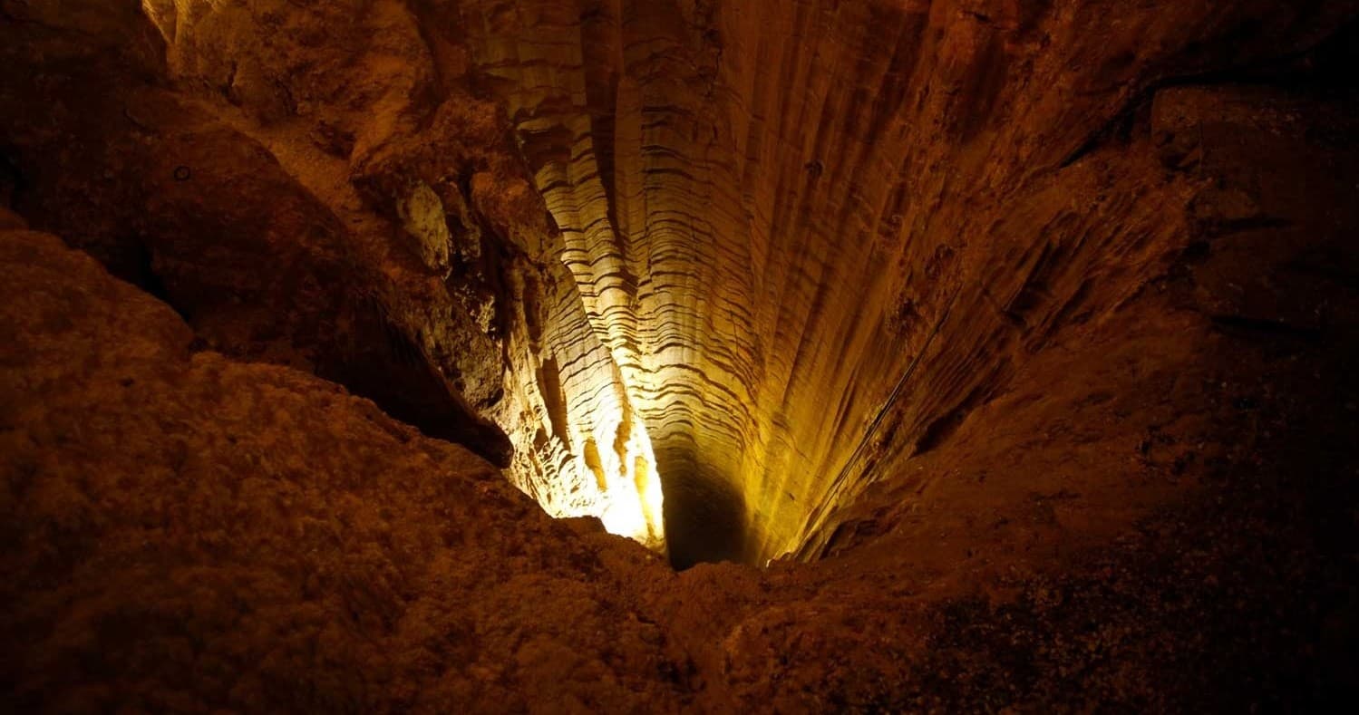 Illuminated cave chamber with narrow shaft for spelunking tours