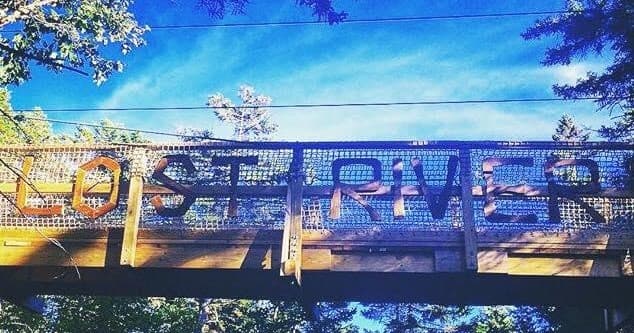 Rustic bridge entrance over forest trail at Lost River
