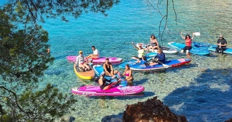 Colorful kayakers paddling in turquoise coastal cove