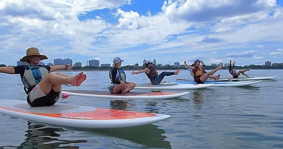 Group stand-up paddleboard yoga session on calm bay waters