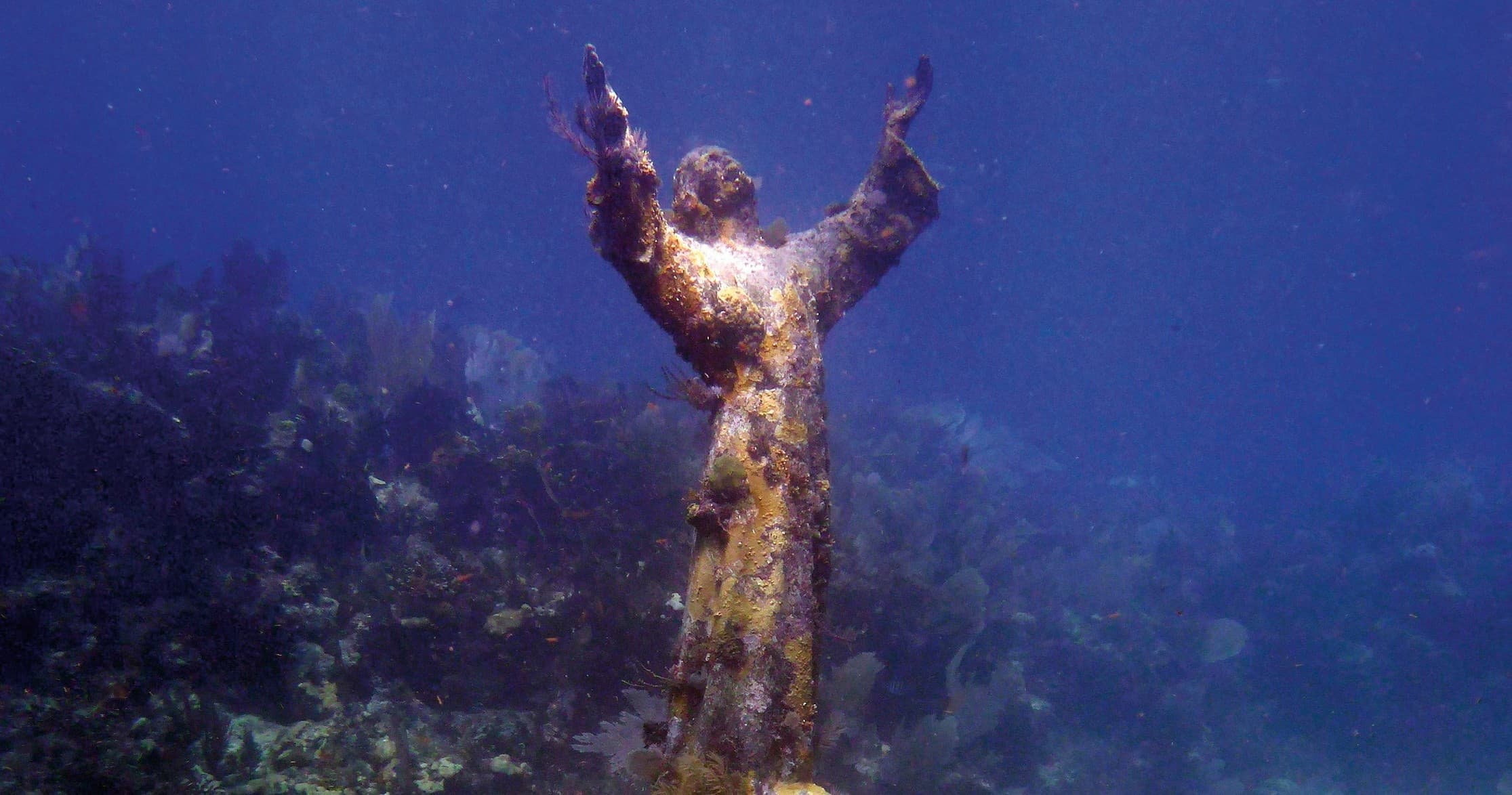 Submerged statue among coral reef, popular scuba diving site