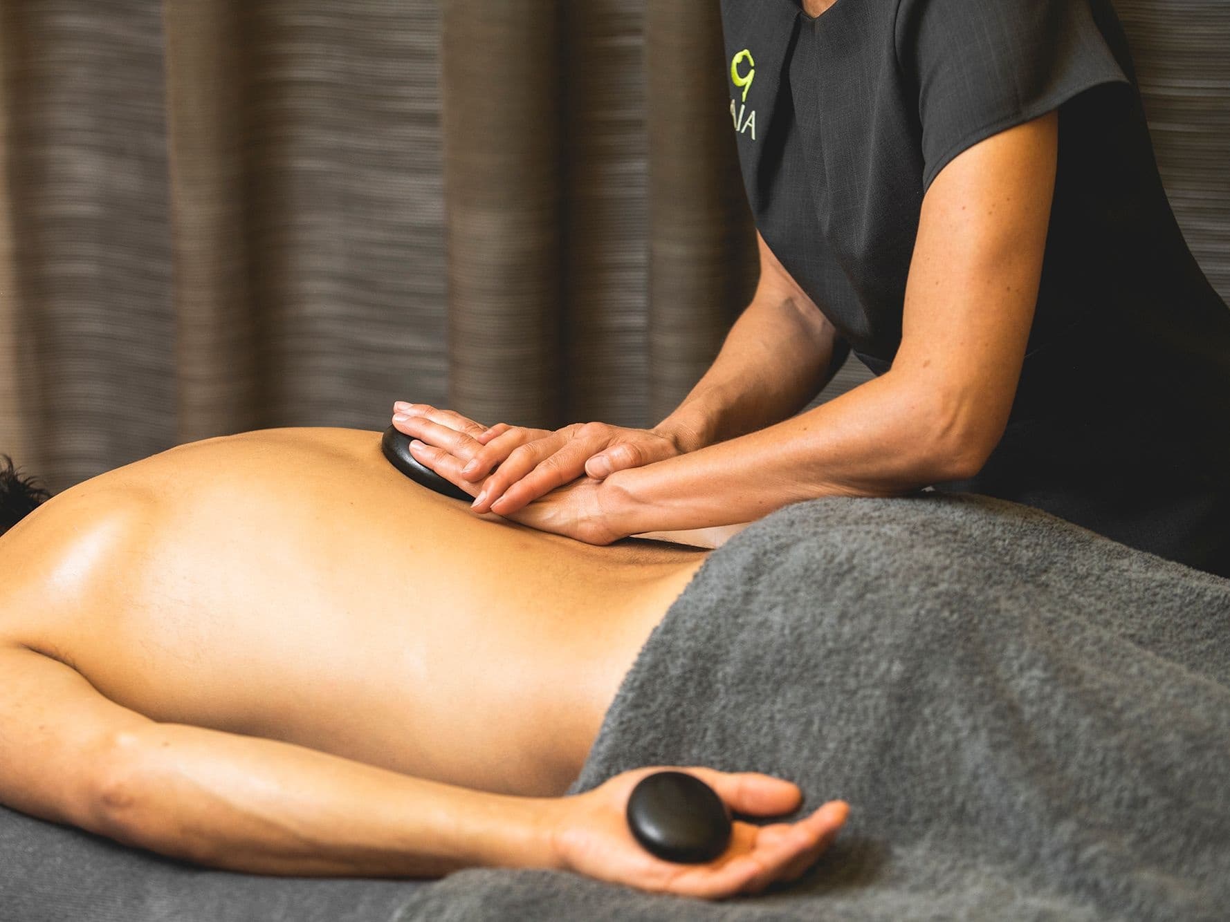 Hot stone massage therapy on client's back in spa
