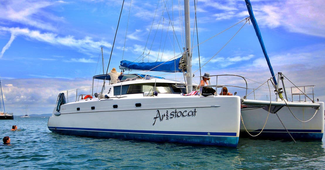 White catamaran anchored in clear blue bay, scenic coastal cruise