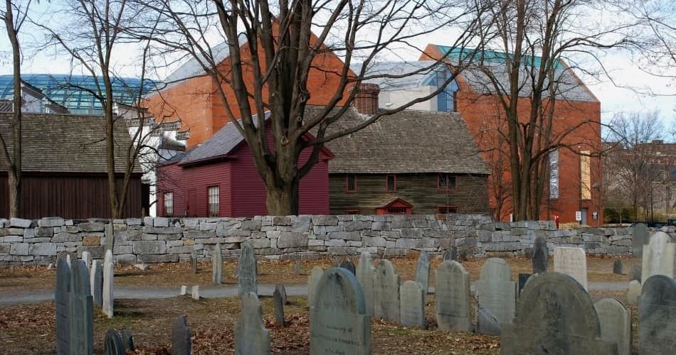Historic Salem graveyard with headstones and colonial buildings