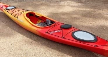 Red and yellow kayak on sandy shore ready for paddling