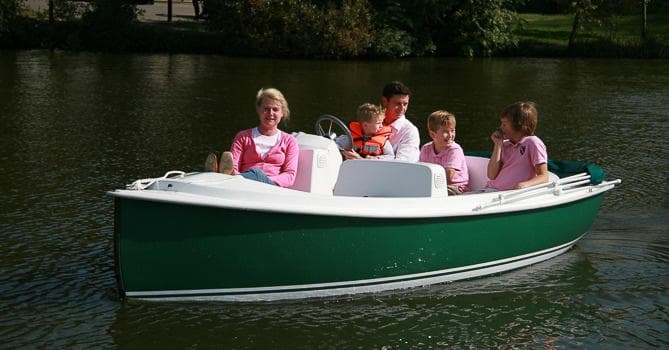 Family riding a green electric boat on park lake outing