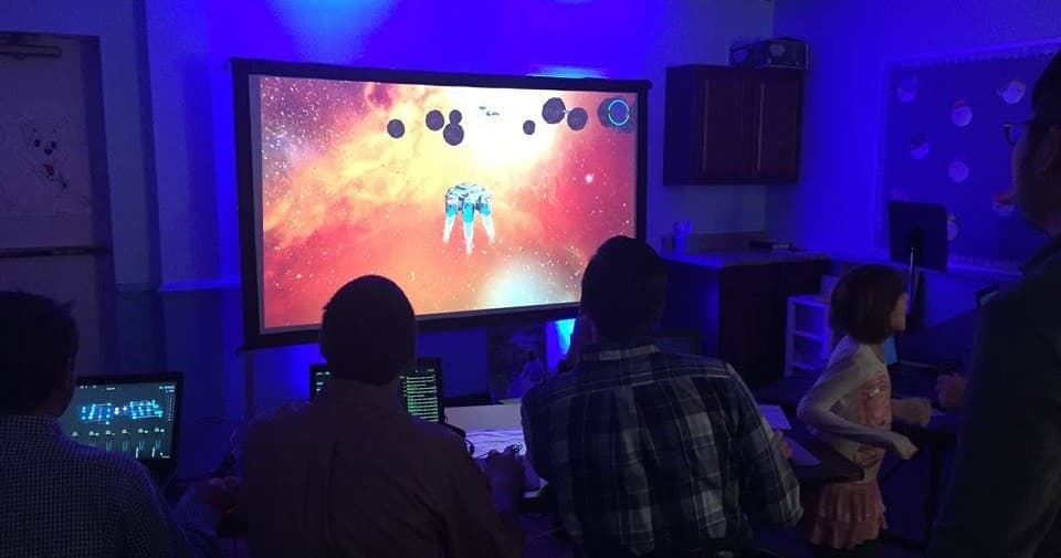 Group playing space shooter game projected on indoor big screen
