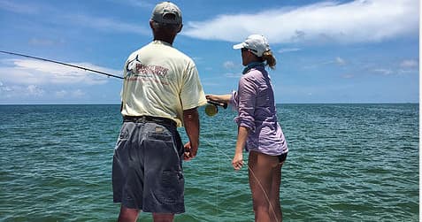 Two anglers fly-fishing on shallow flats in turquoise ocean