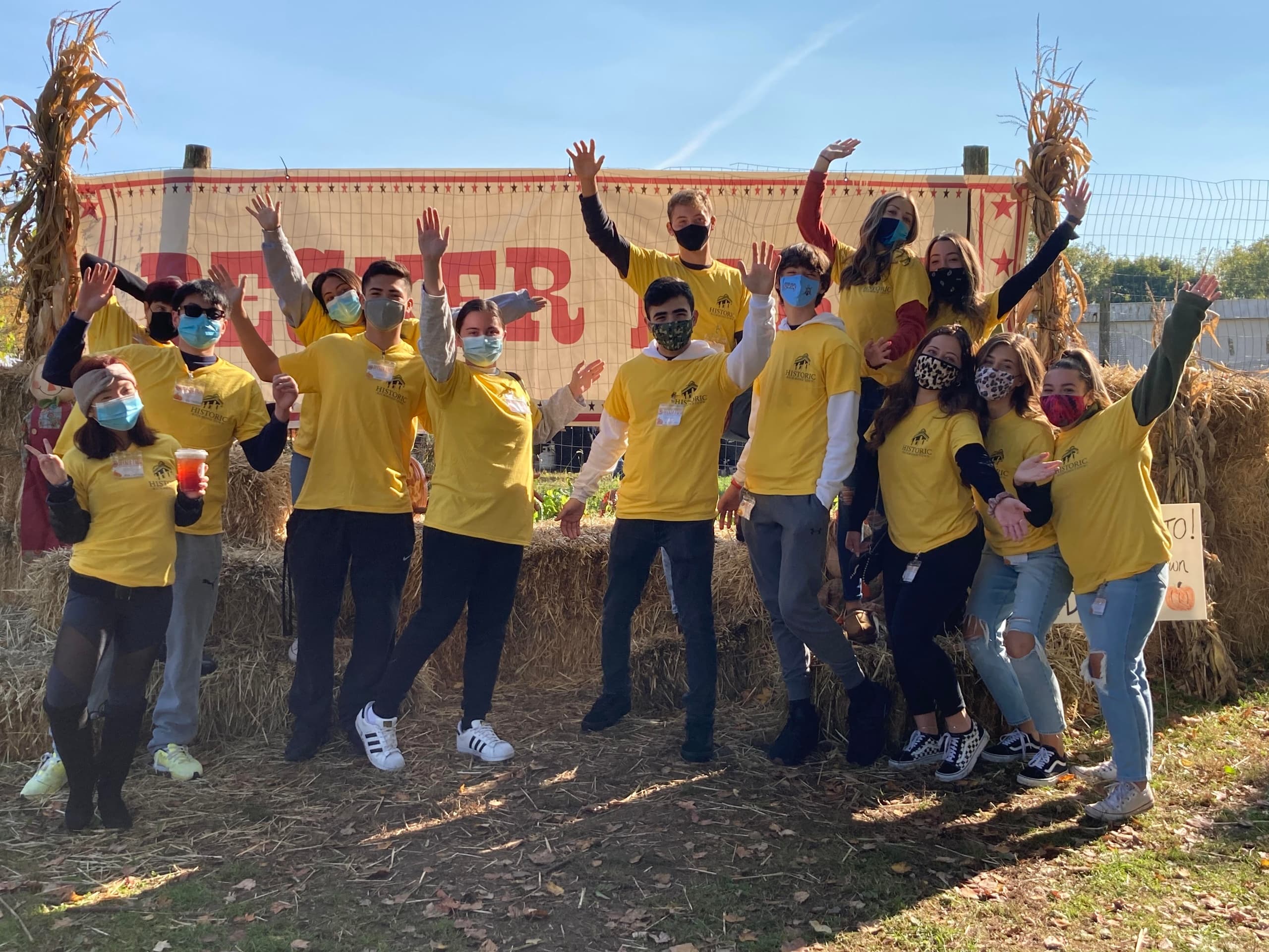 Volunteer group in yellow shirts at autumn farm festival outdoors