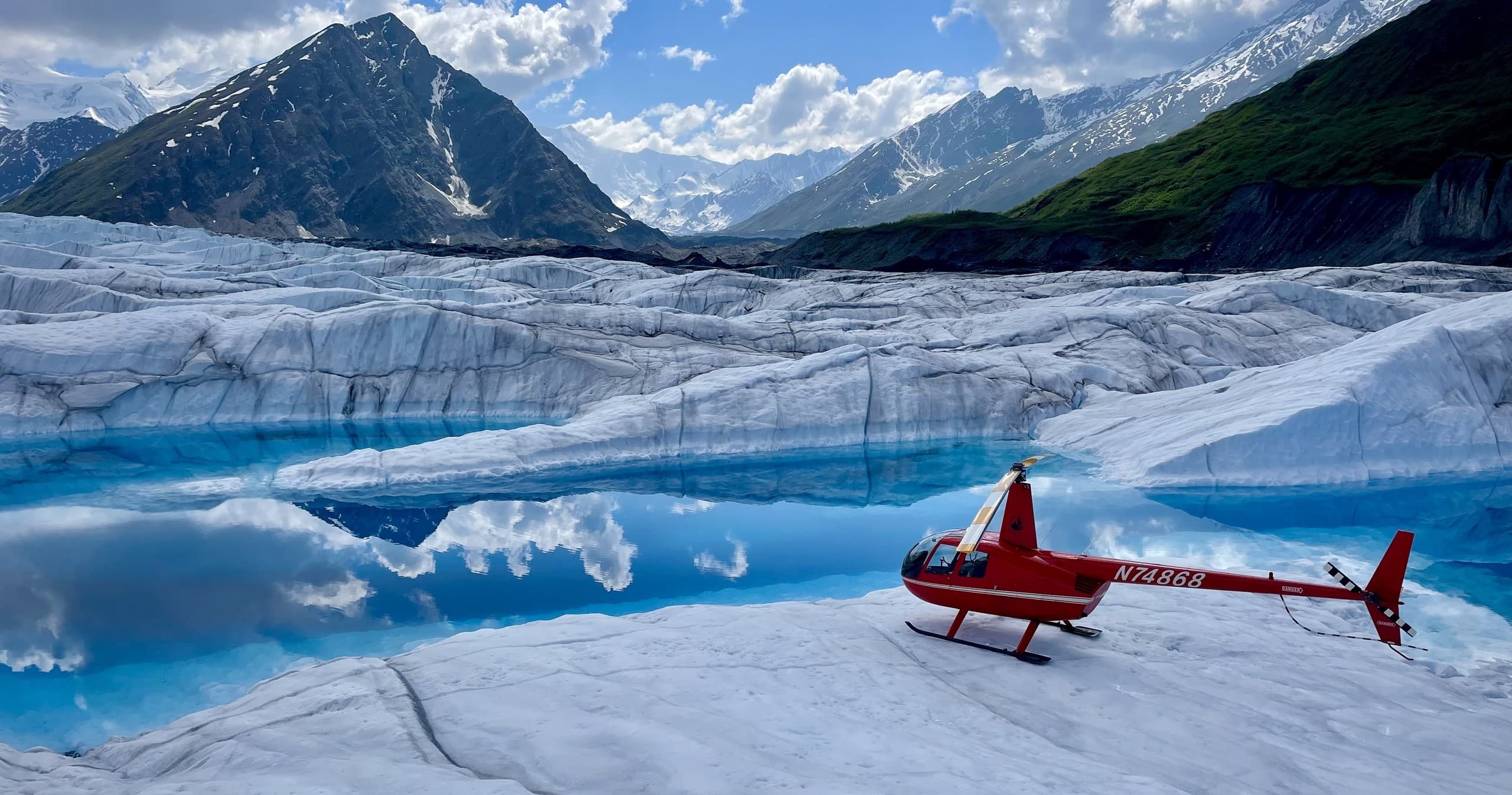 Scenic helicopter tour parked beside mirrored glacier lake and peaks