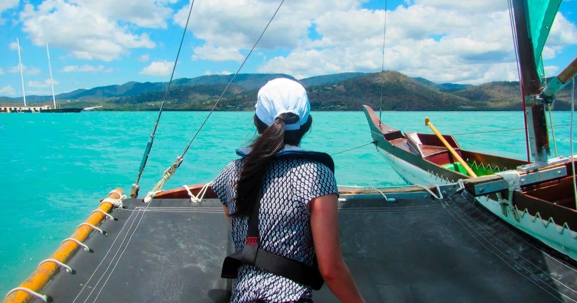 Rear view of sailor on outrigger overlooking turquoise Whitsundays sea