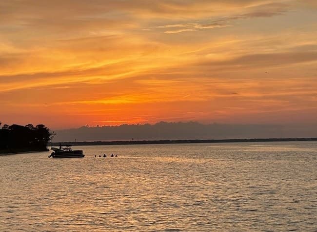 Golden sunset over tranquil bay with distant anchored boat