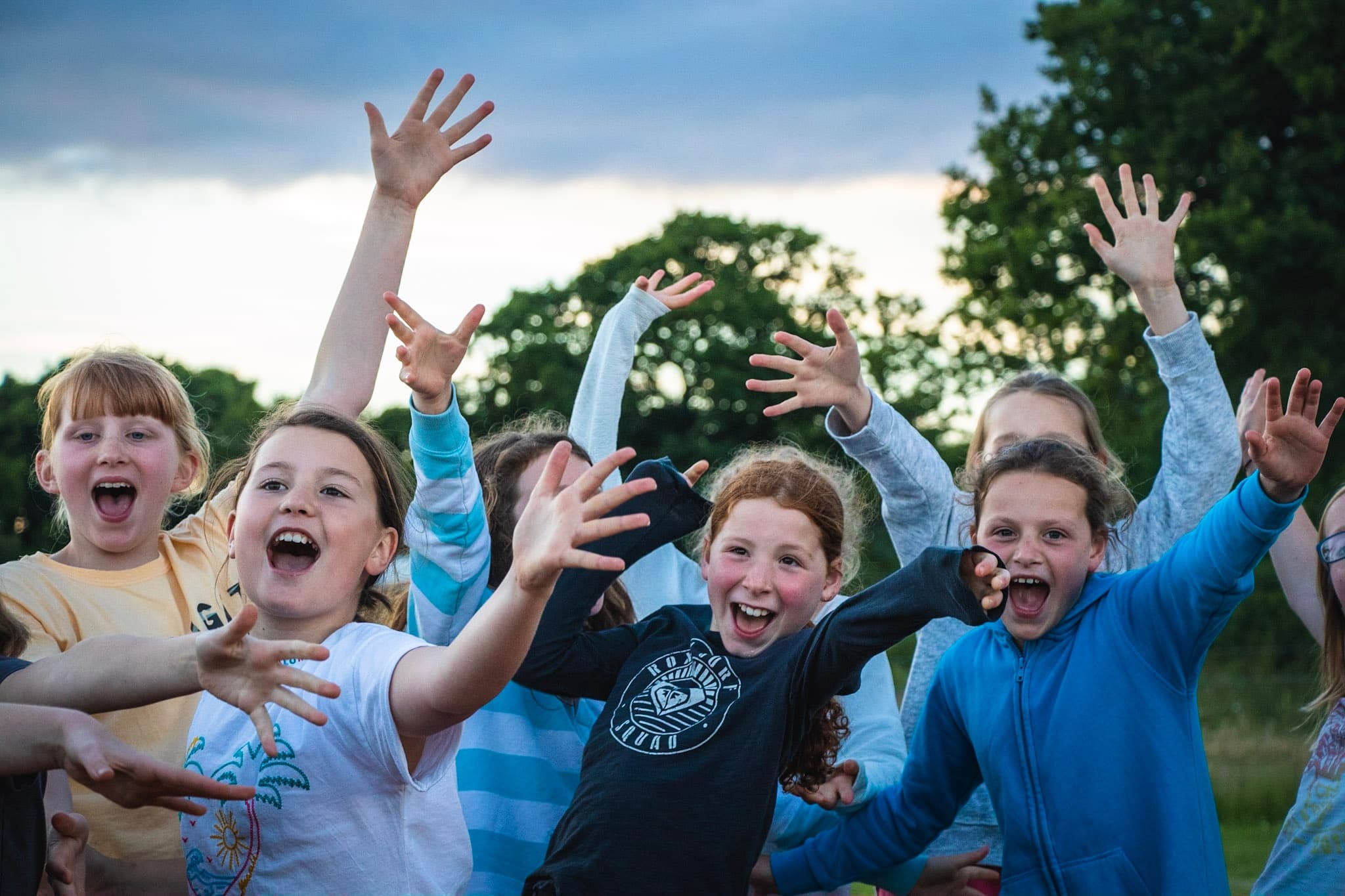 Children cheering outdoors at summer adventure camp in countryside