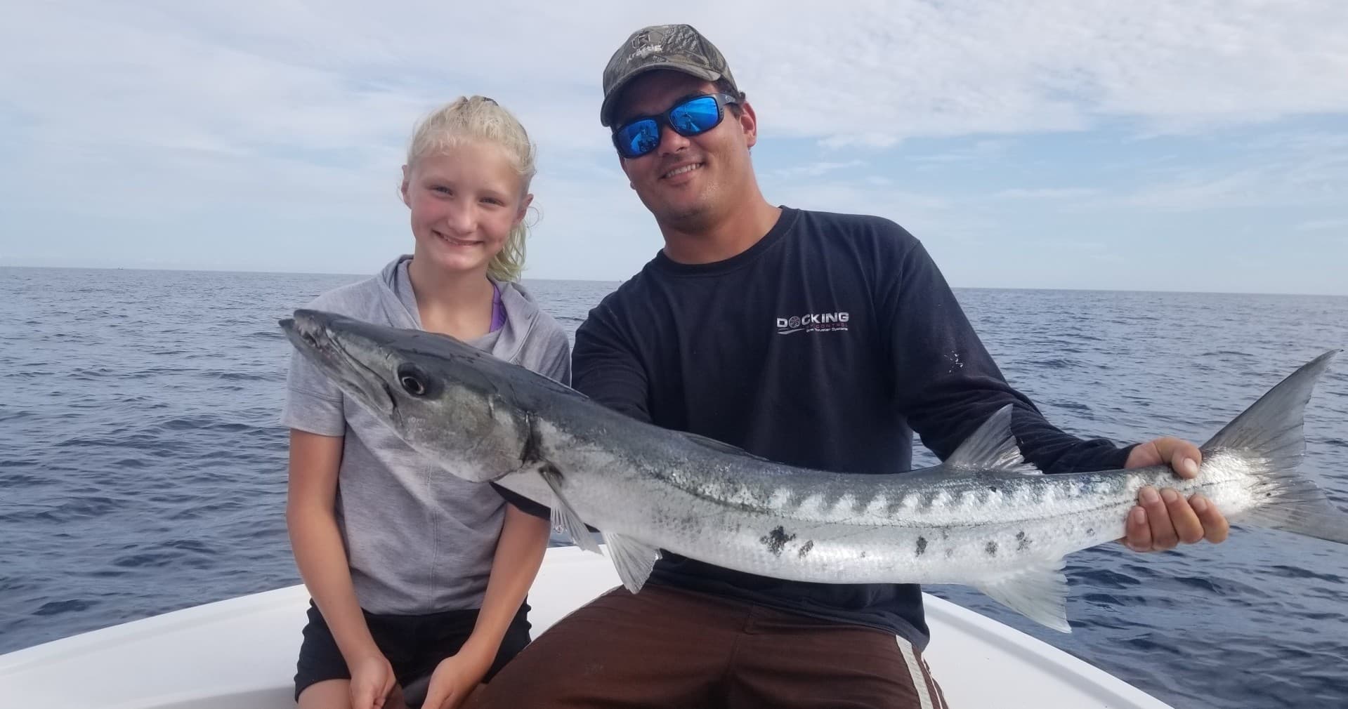 Family holding big barracuda on recreational fishing charter