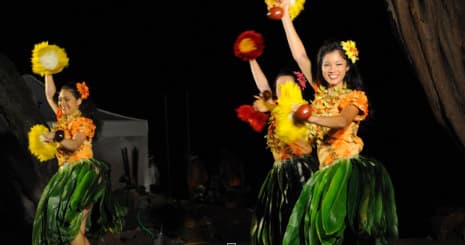 Hula dancers in floral leis performing night show outdoors