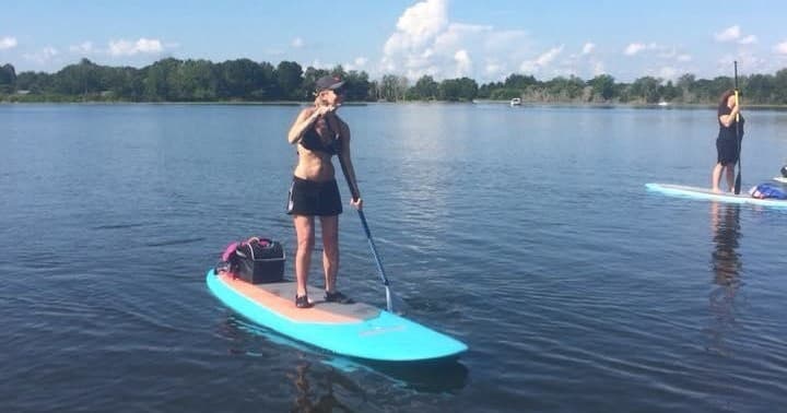 Solo paddleboarder paddling on tranquil lake shoreline