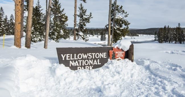 Yellowstone National Park sign in snowy winter park entrance