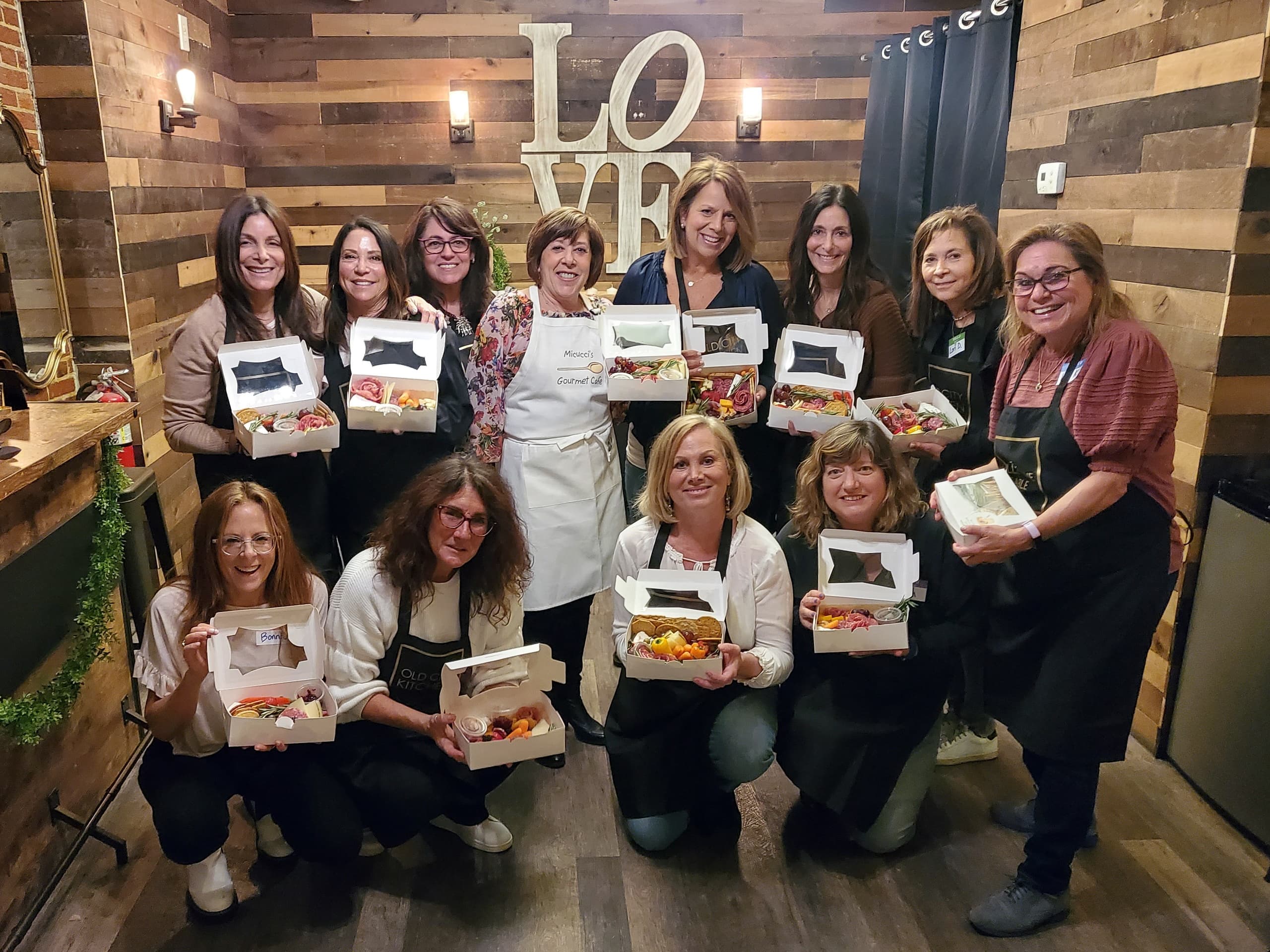 Cooking class group indoors holding finished dishes, kitchen workshop