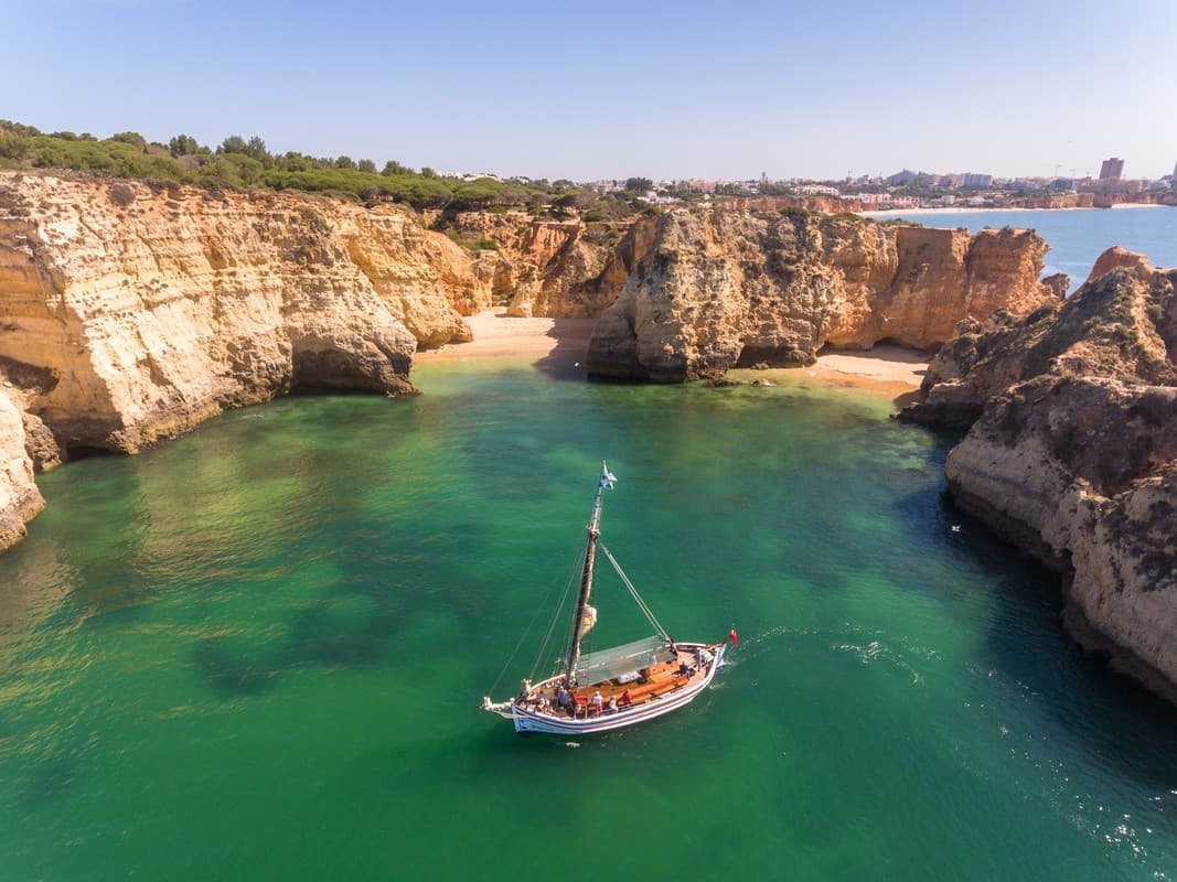 Small sailboat anchored inside scenic limestone cove, ocean