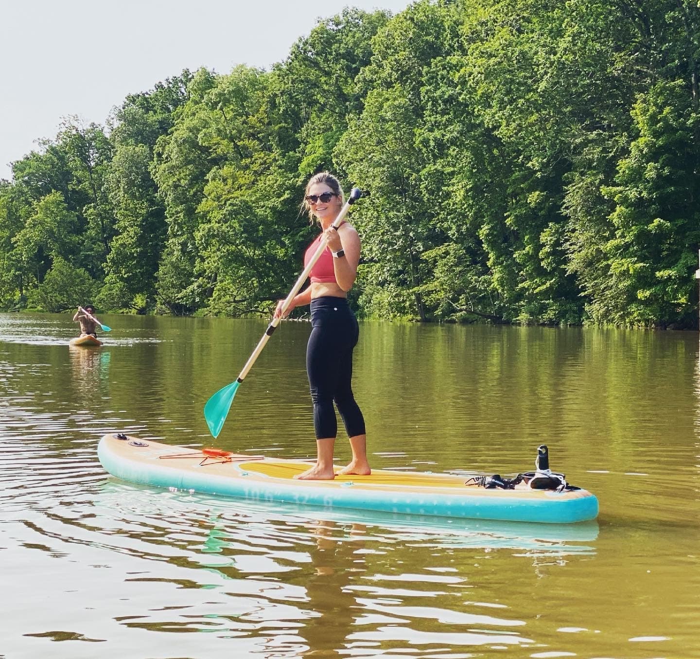 Stand-up paddleboard on calm lake near tree-lined shoreline