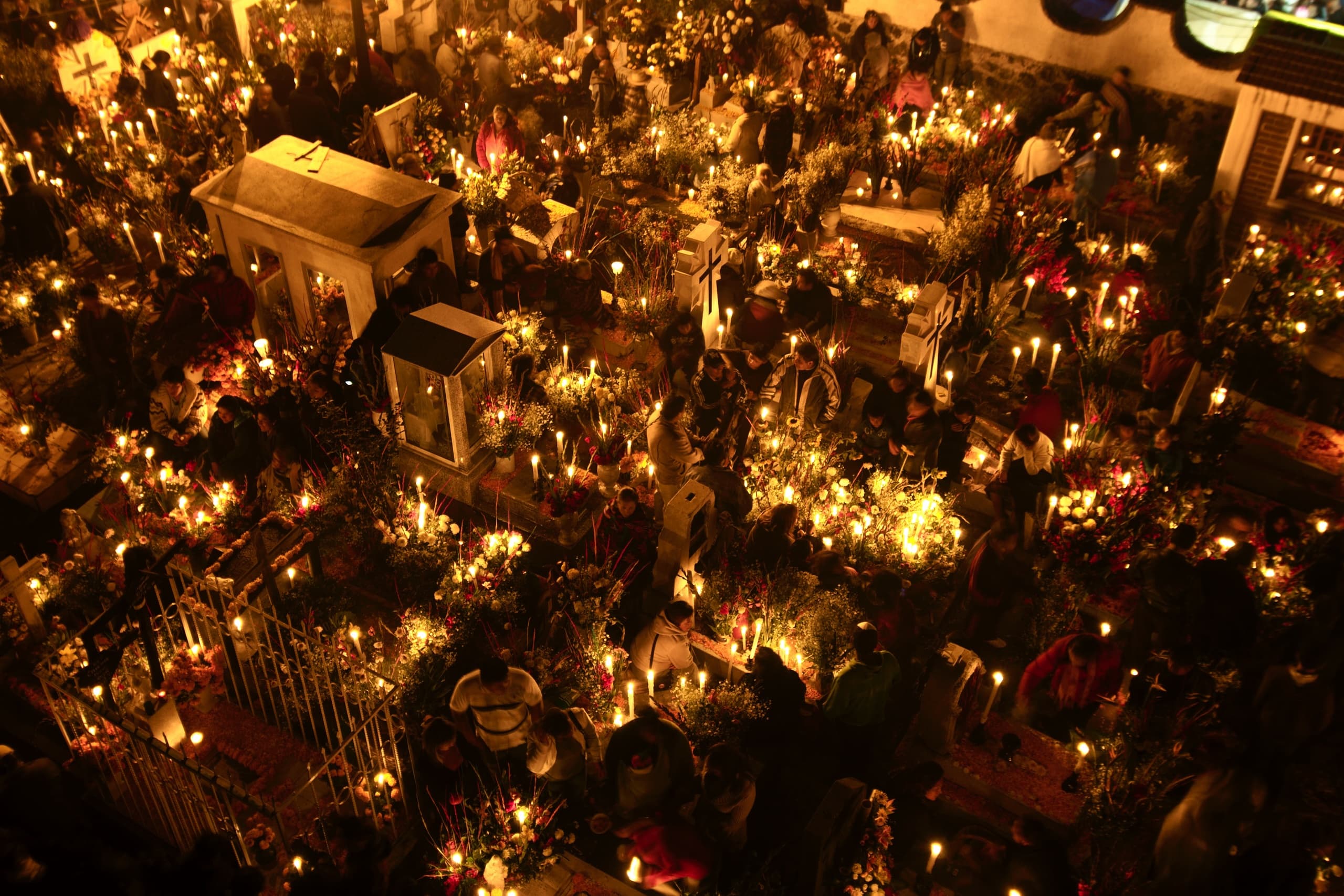 Nighttime candlelit Día de los Muertos cemetery altar scene