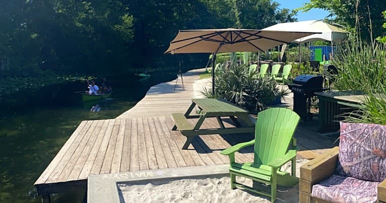 Wooden dock with green chairs on tranquil riverfront cove