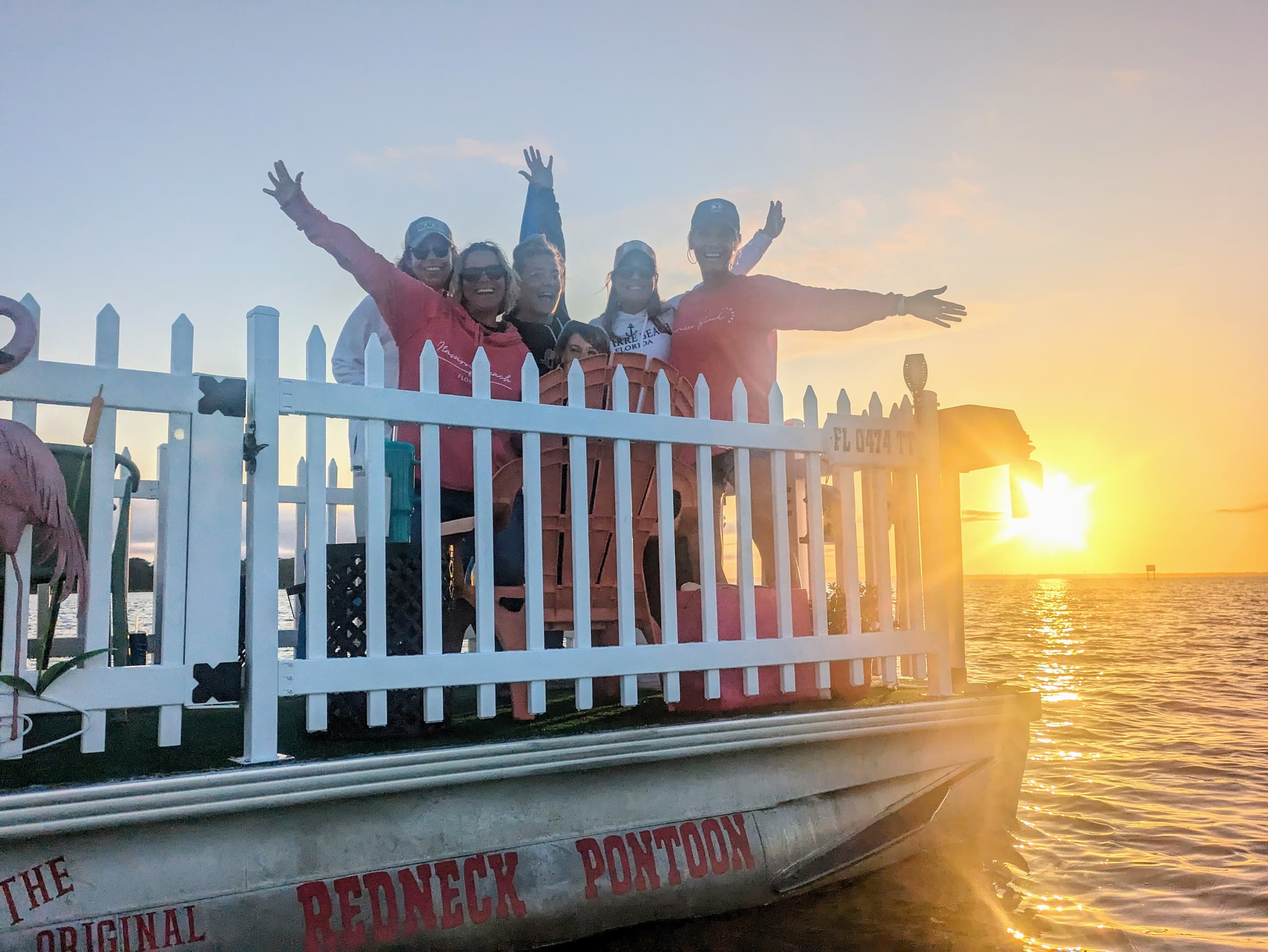 Group on pontoon at sunset celebrating over calm sea