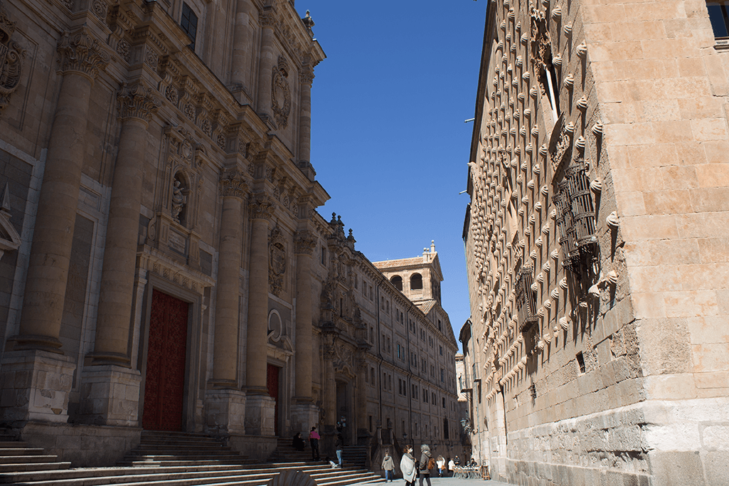 Sunlit narrow Salamanca street between historic sandstone buildings