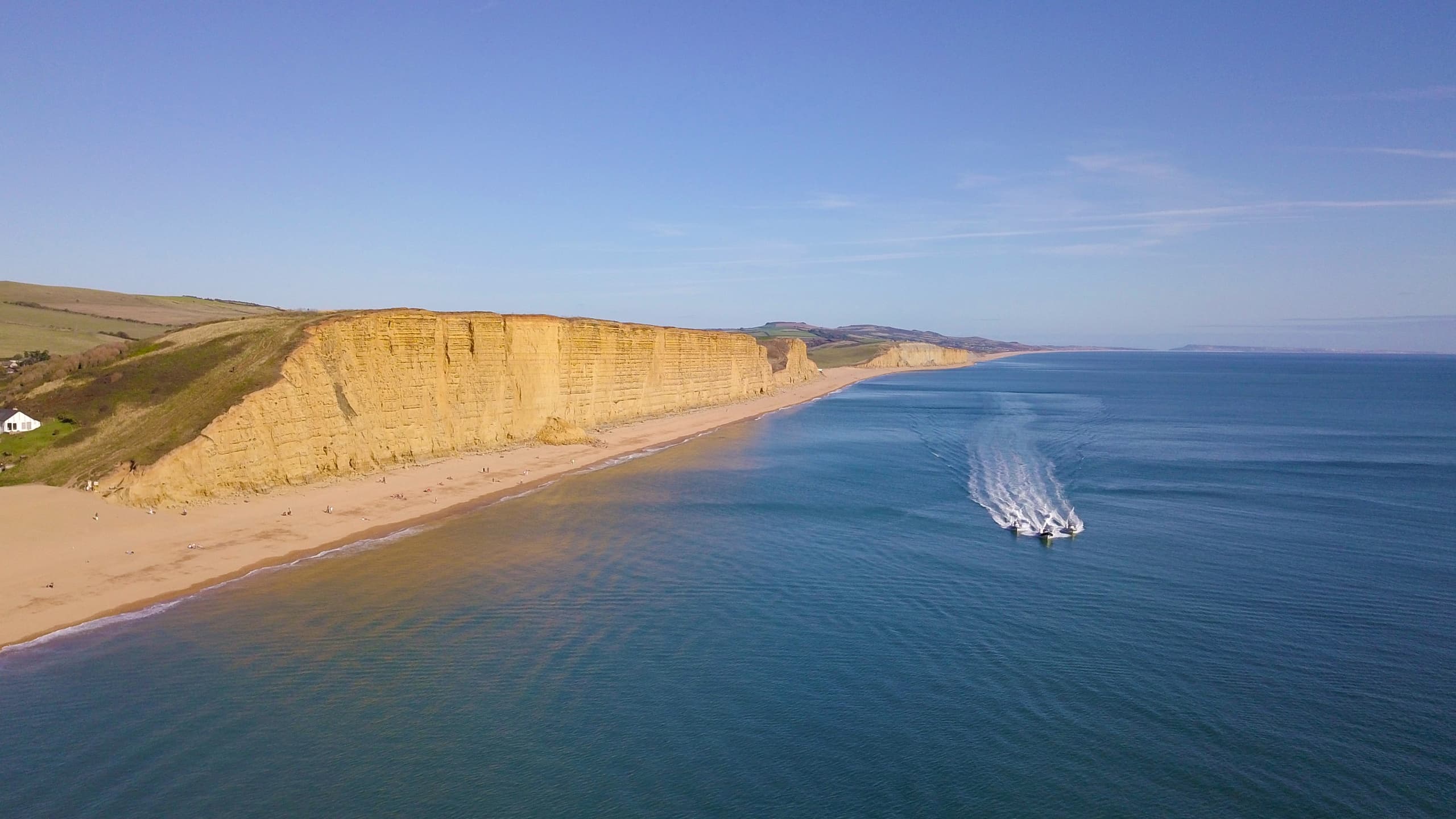 RIB boat cruising along golden Lyme Bay cliffs, coastal tour