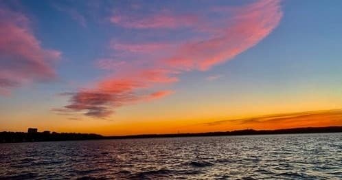 Sunset boat cruise over coastal waters with colorful sky