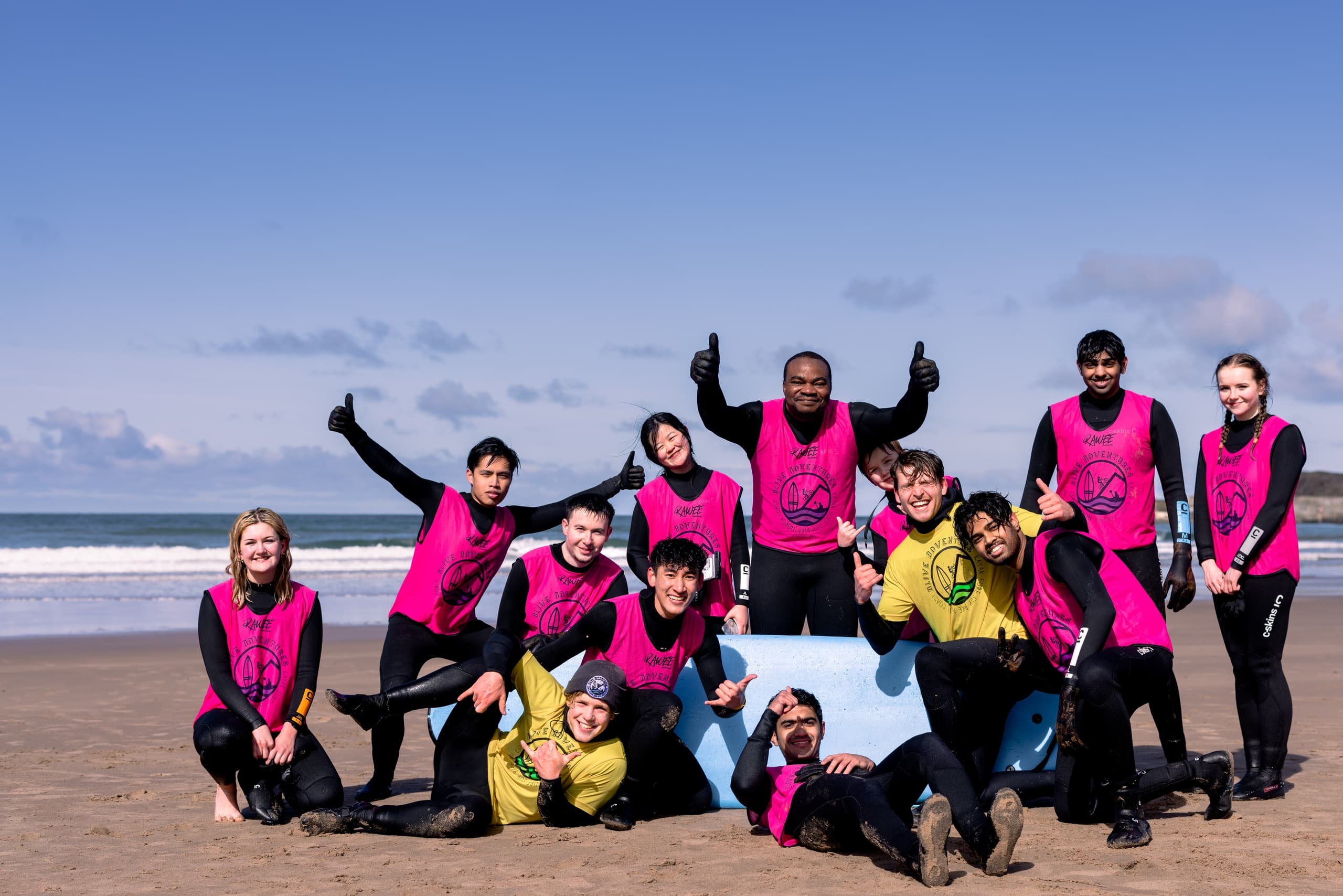 Surf school group posing on sandy beach by ocean